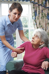 elderly woman being helped out of a chair by an upset employee of nursing home