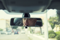 fatigued driver visible in a rearview mirror