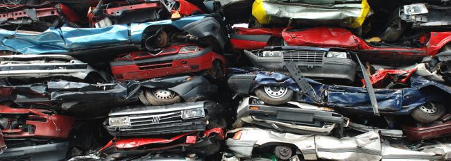 totalled cars stacked at a salvage yard