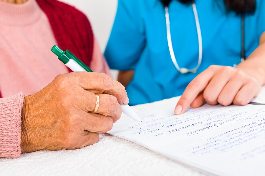 Nursing staff helping an elderly woman write a letter to relatives