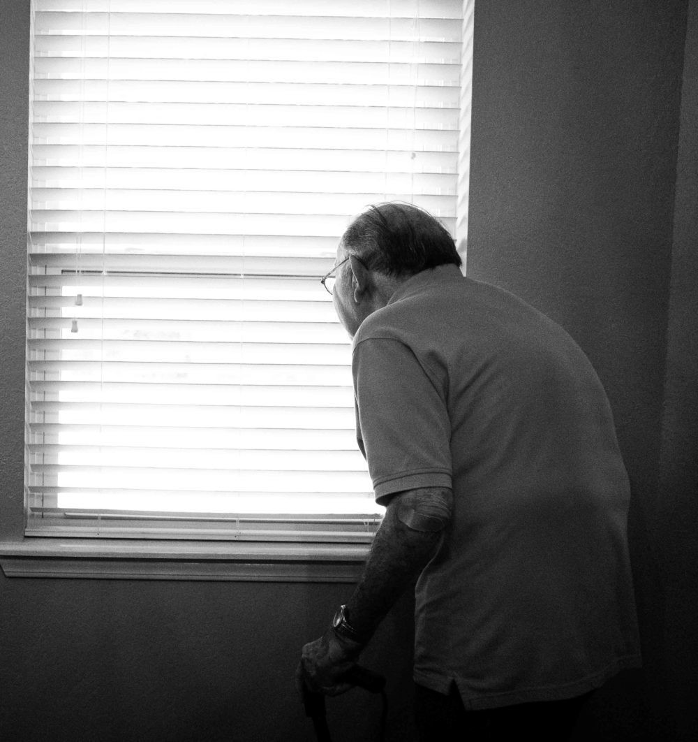 old man looking out the window of a nursing home.