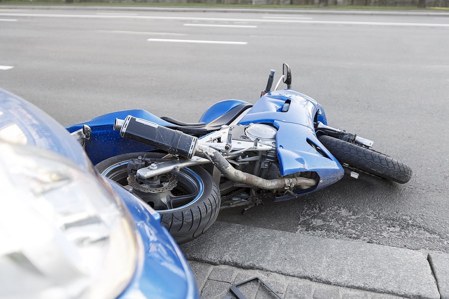 Blue motorcycle laying on its side after a collision