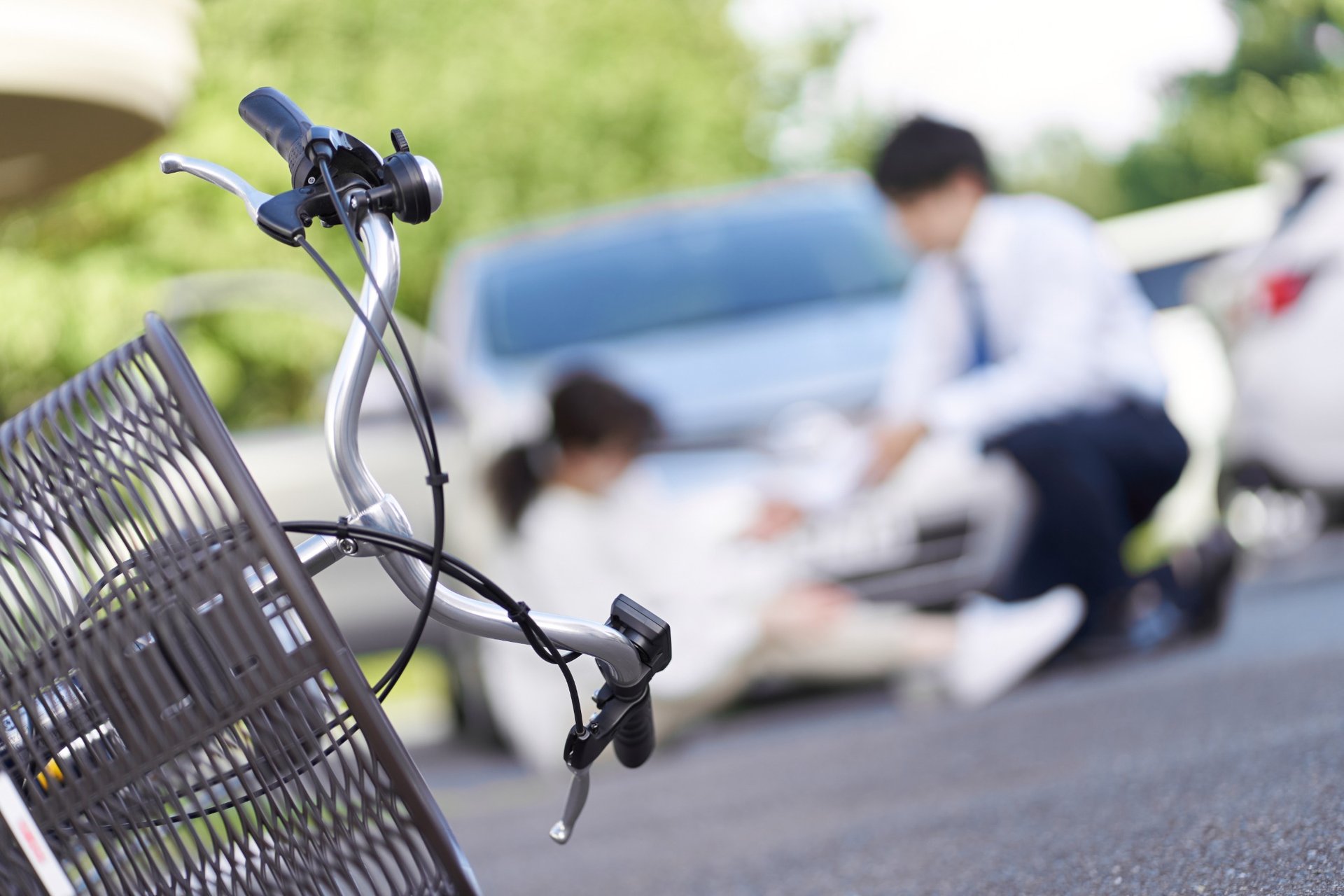 Bicycle in foreground with a car accident and injured person blurred in the background