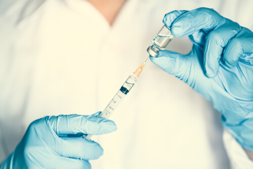 medical professional holding a syringe and medicine bottle