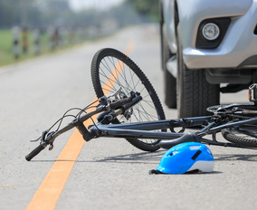 Silver car hits cyclist, causing a Bicycle accident in the road