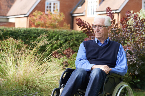 elderly man sitting in a wheelchair outside of a nursing home