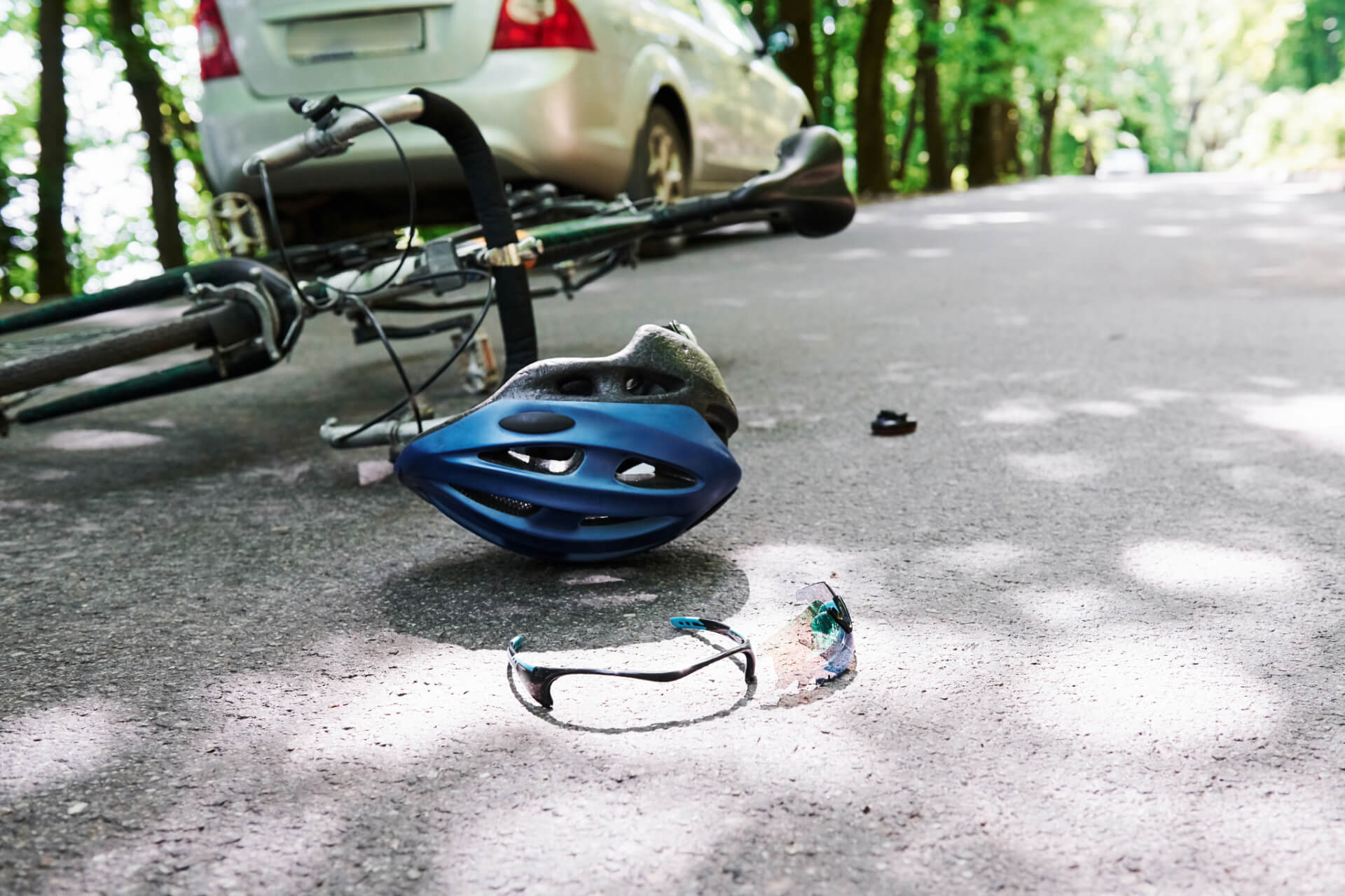 bicycle and helmet lying on the ground next to a car