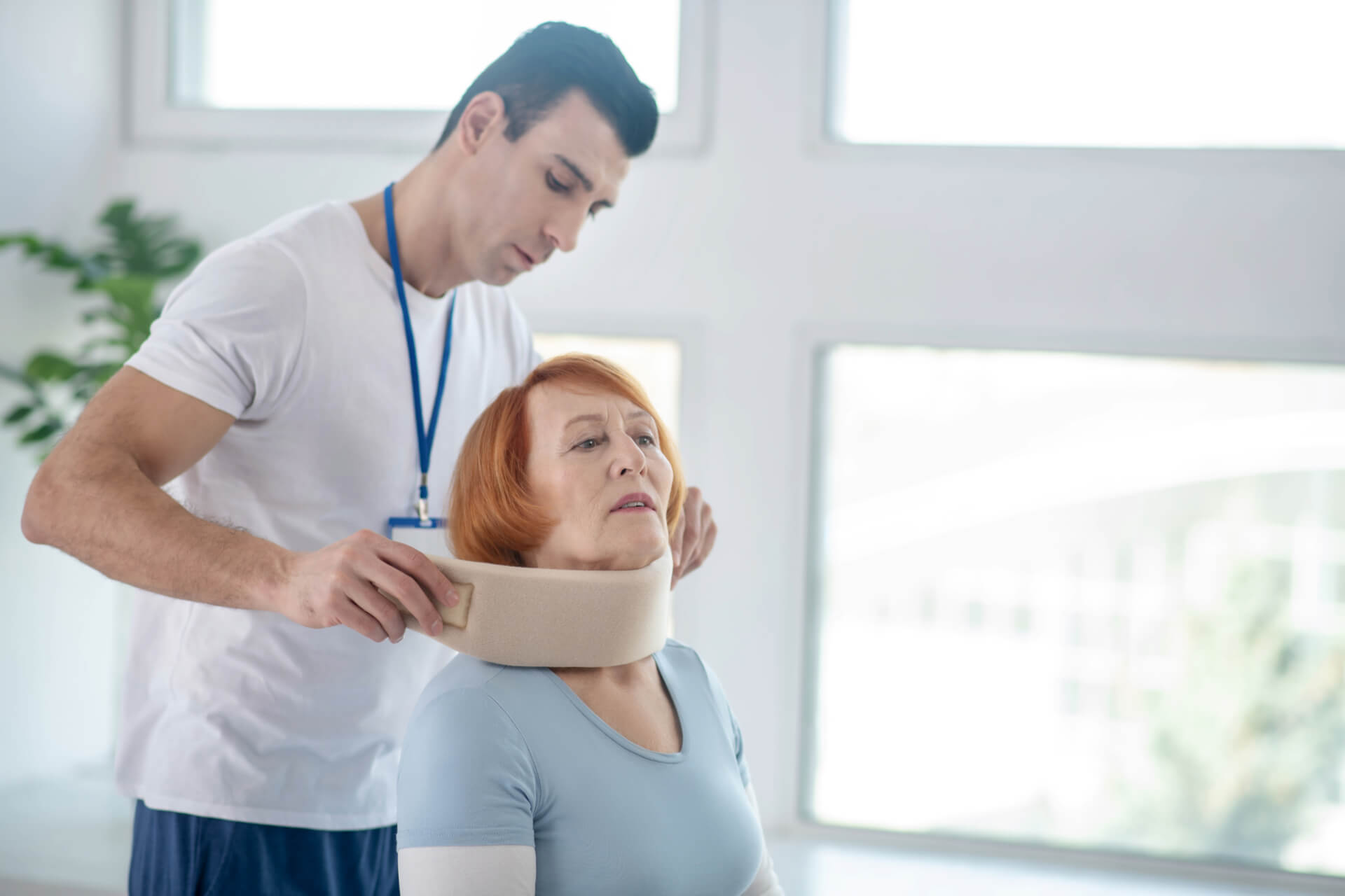 professional male doctor putting neck collar on female patient