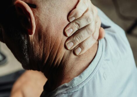 Close up of person with neck pain or injury with hand placed on neck and shoulder area