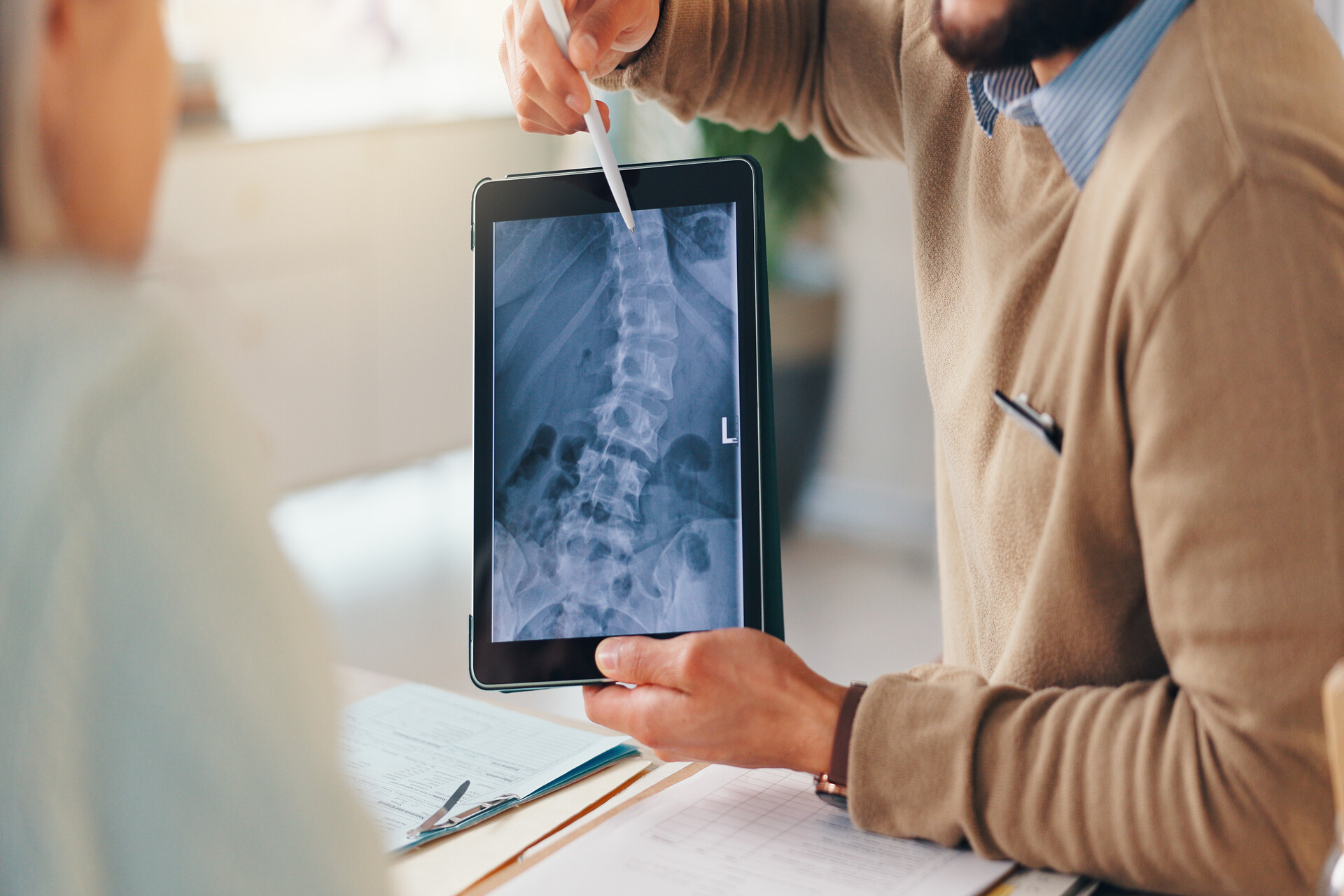 Doctor showing spinal X-ray on tablet