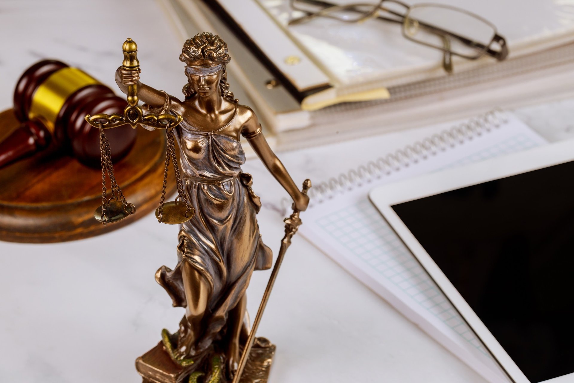 Close-up of Lady Justice statue with legal documents and gavel