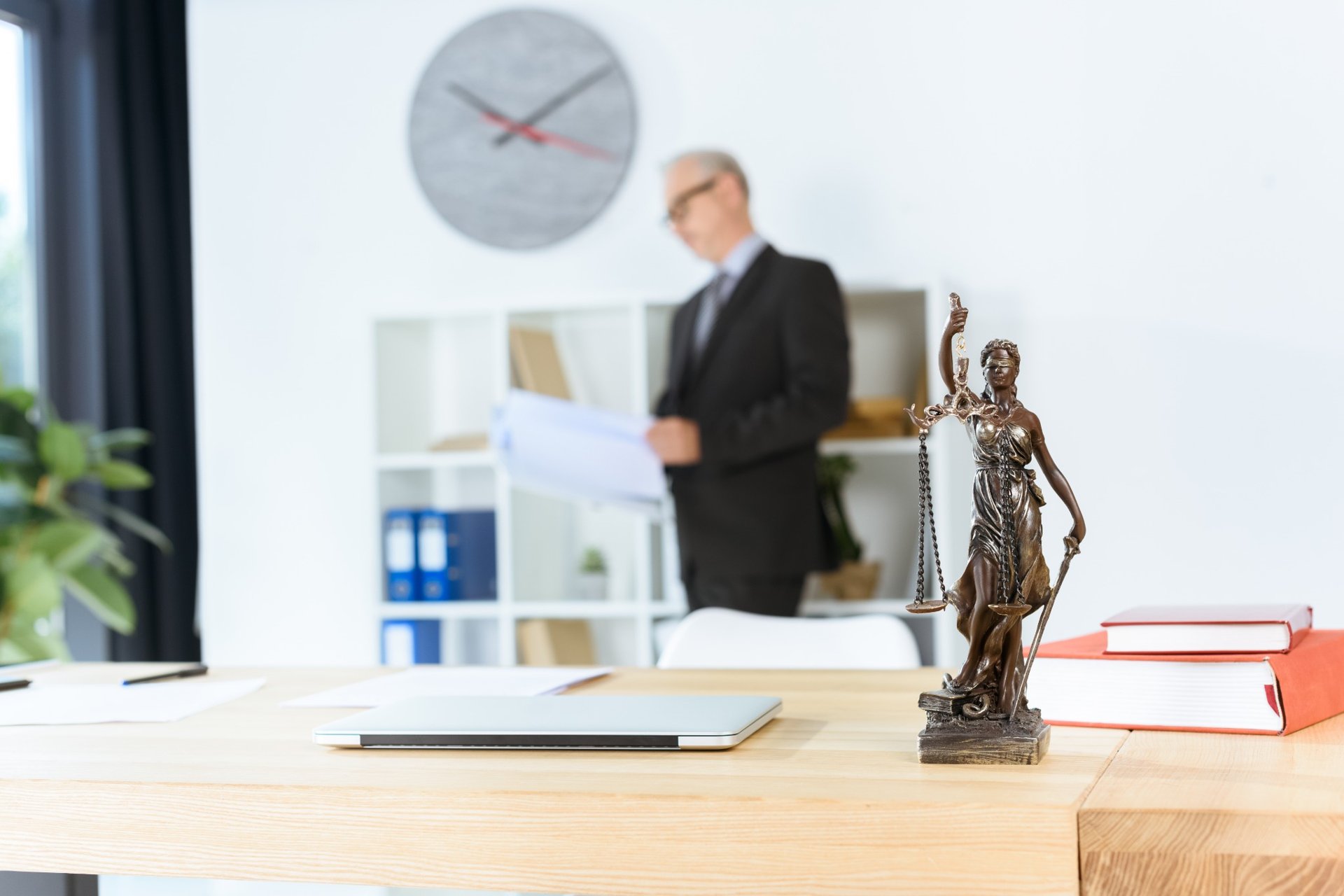 Lady Justice statue on legal office desk with blurred lawyer