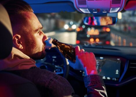 Man drinking beer while driving at night