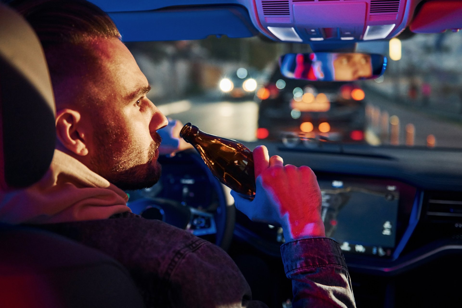 Man drinking beer while driving at night