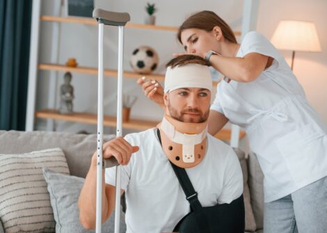 Nurse caring for an injured man wearing a neck brace and arm sling