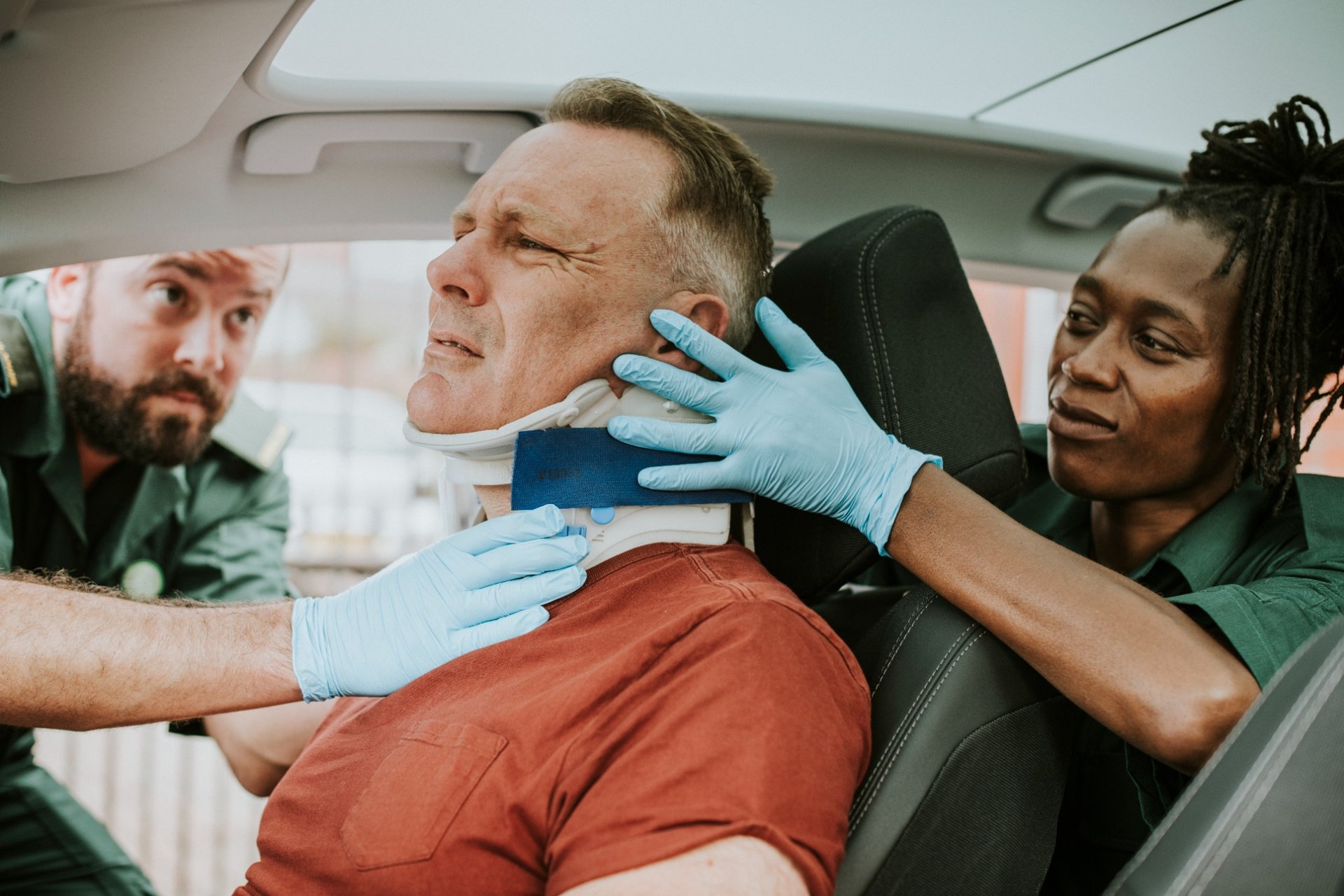 Paramedics assisting a man with a neck injury after a car accident