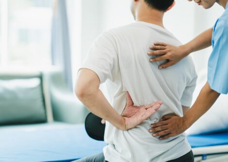 Therapist assisting a man with lower back pain during a physiotherapy session