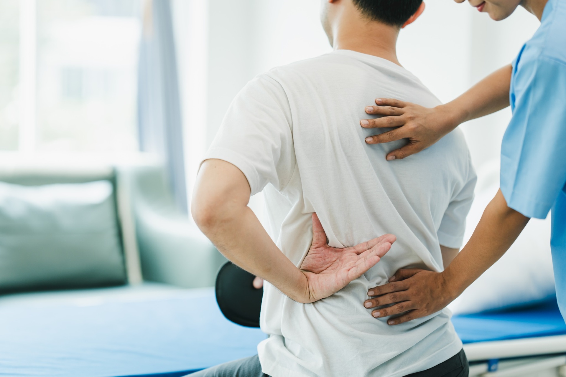 Therapist assisting a man with lower back pain during a physiotherapy session