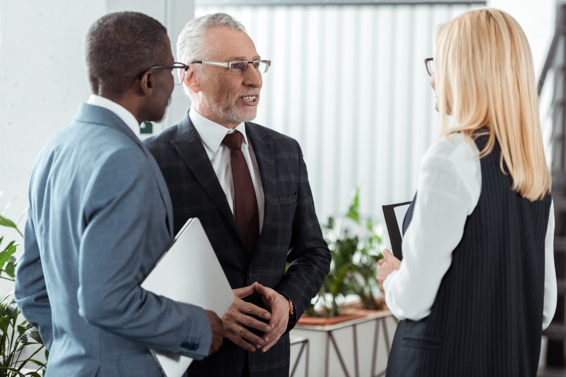 Three business professionals having a discussion in a bright office setting