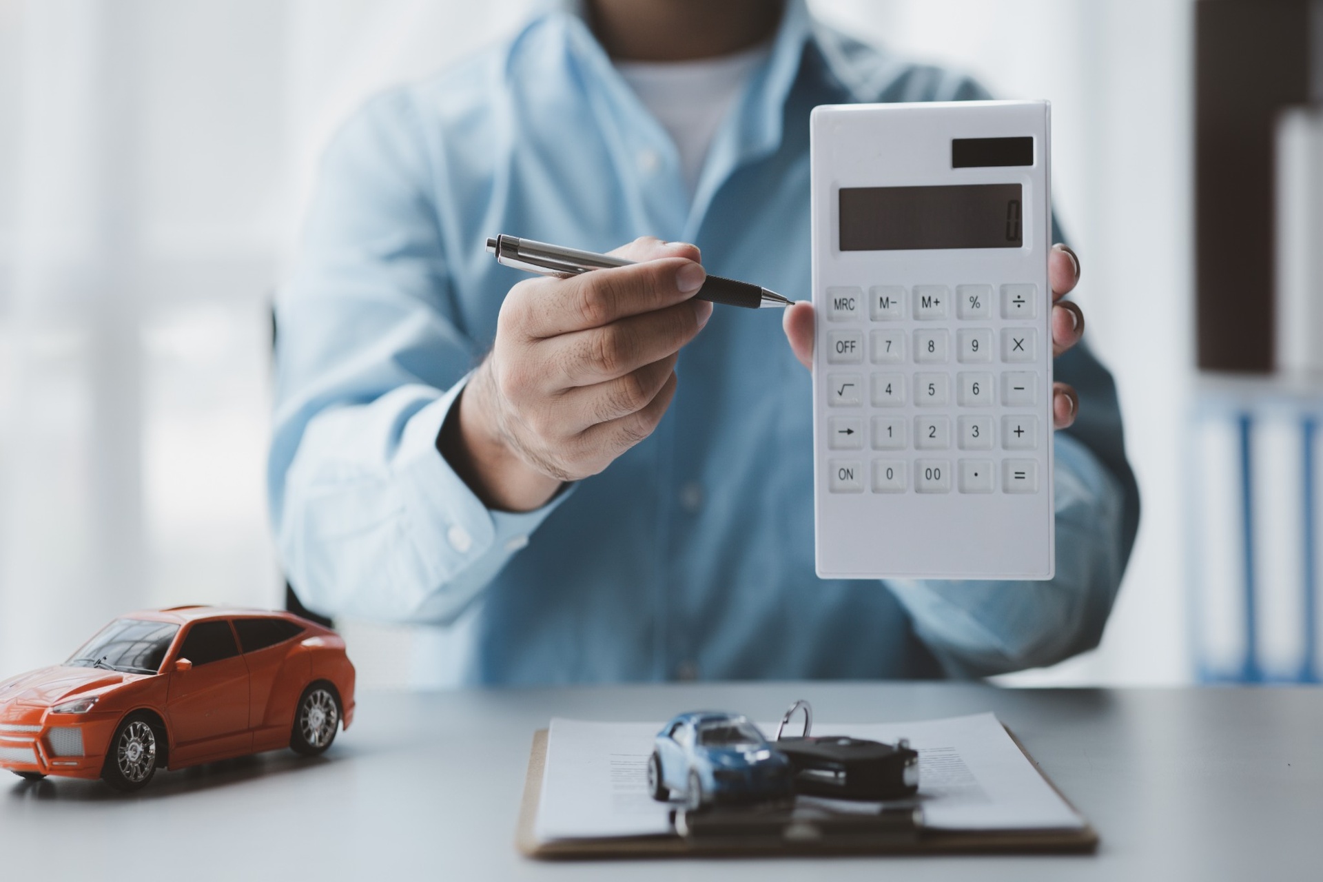 Insurance agent showing calculator with toy cars on desk
