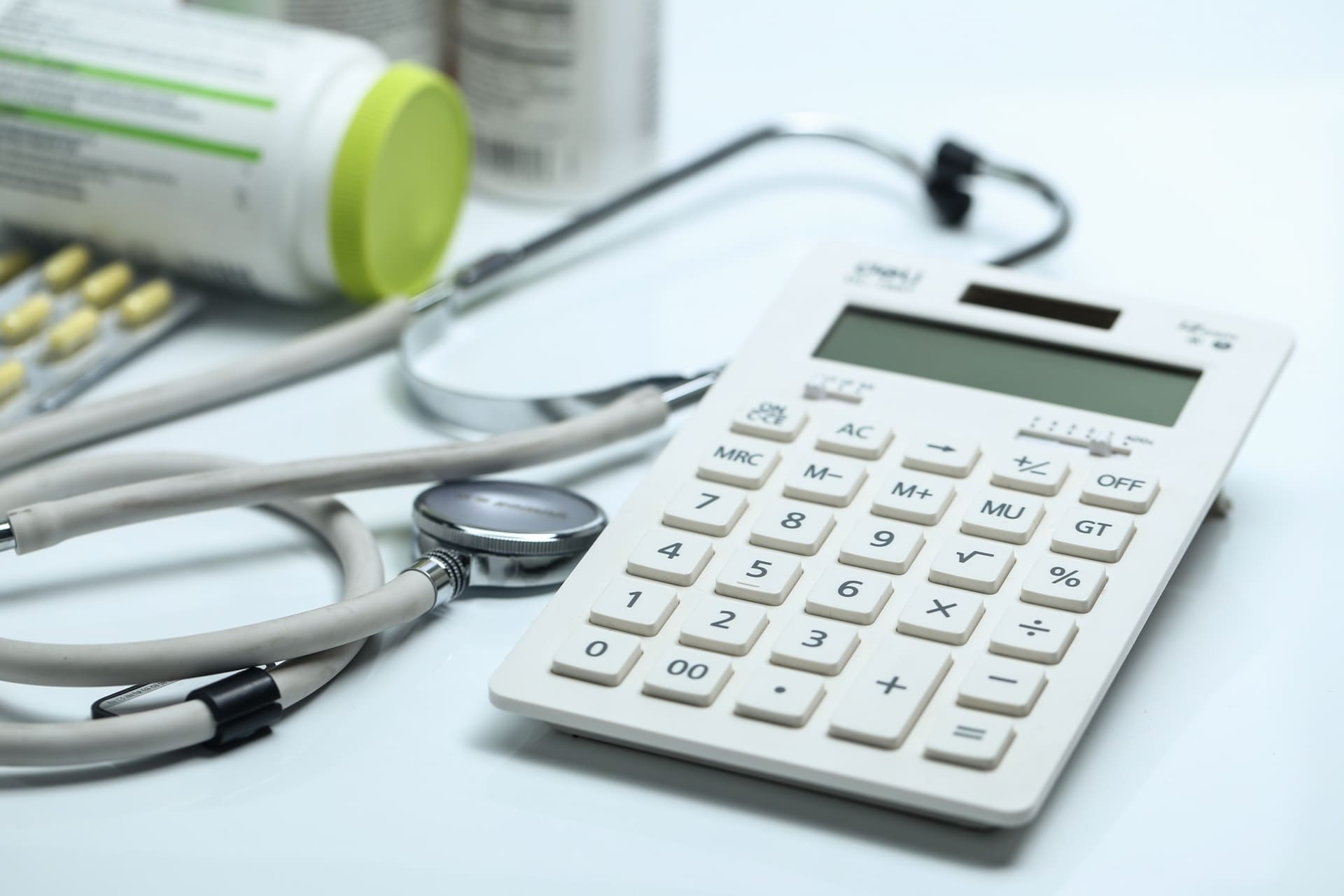 calculator stethoscope medicine bottles on the desk
